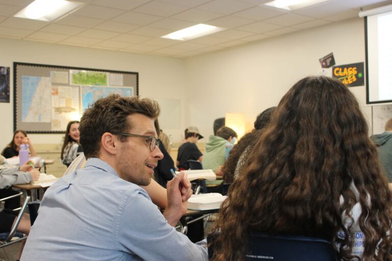 Teacher crouches down to help student in class at West Hills Christian School.