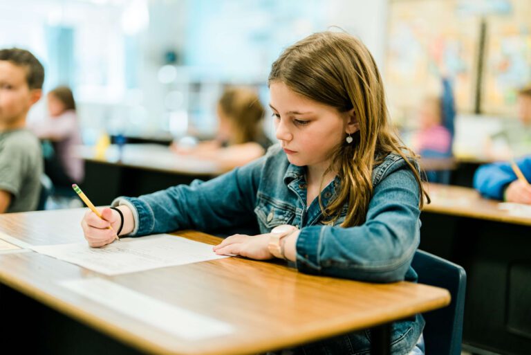 Elementary girl writes at desk.